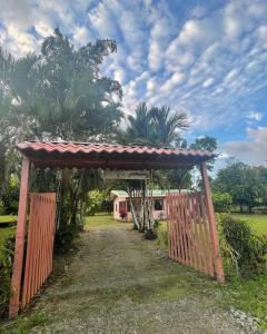 a wooden gate leading to a house with palm trees at Villa Montezuma Corcovado in Puerto Jiménez
