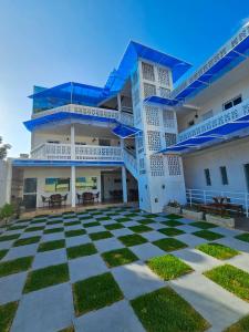 Un grand bâtiment blanc avec des balcons bleus et une terrasse est disponible. dans l'établissement MANERO POUSADA e HOSTEL, à Natal