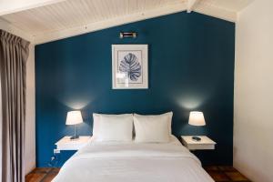 a bedroom with a blue wall with a bed and two lamps at Hotel Rip Jack Inn in Playa Grande