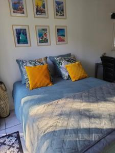 uma cama com lençóis azuis e almofadas amarelas em Logement La Belle Provence em Le Beausset