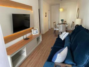 uma sala de estar com um sofá azul e uma televisão de ecrã plano em Apartamento Alto padrão na praia do forte em Cabo Frio