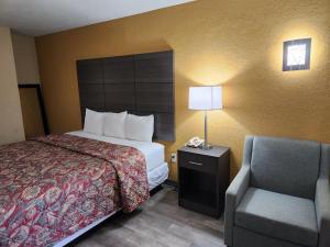 um quarto de hotel com uma cama e uma cadeira em Days Inn by Wyndham Charlotte Northlake em Charlotte