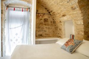 een slaapkamer met een wit bed en een stenen muur bij Mazzini 5 in Ragusa