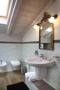 La salle de bains est pourvue d'un lavabo, de toilettes et d'un miroir. dans l'établissement Corte San Luca Apartments, à Bardolino