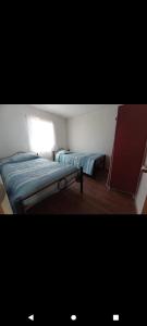 a small bedroom with two beds and a window at Hermosa cabaña para 4 personas con tinaja-Cochiguaz Valle de Elqui in Monte Grande