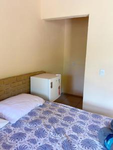 a small bedroom with a bed and a refrigerator at Chalé Sol in Pacoti