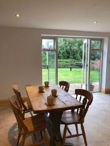 einen Holztisch und Stühle in einem Zimmer mit Fenster in der Unterkunft Stylish Barn Conversion with Woodland Views in Newark upon Trent