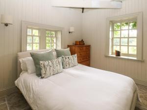 a white bed in a bedroom with two windows at The Courtyard in Carlisle