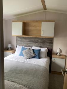 a bedroom with a bed with blue and white pillows at Splendid View Caravan in Gisburn