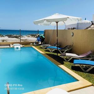 einen Pool mit Stühlen, einem Sonnenschirm und einem Sonnenschirm in der Unterkunft DIAR SIDI VILLAS DE LUXE in Kelibia