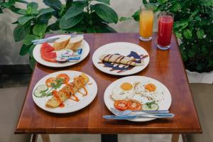 - une table en bois avec des assiettes de nourriture pour le petit-déjeuner dans l'établissement Shogun Hotel, à Hô-Chi-Minh-Ville
