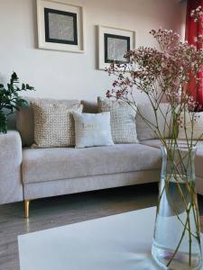 sala de estar con sofá y jarrón con flores en Comfortable Apartament en Katowice