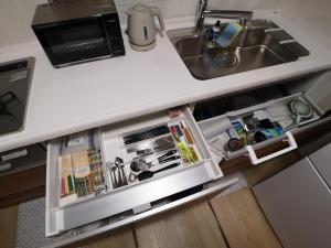 an open refrigerator underneath a kitchen counter next to a sink at YUKIMARU in in Tokyo