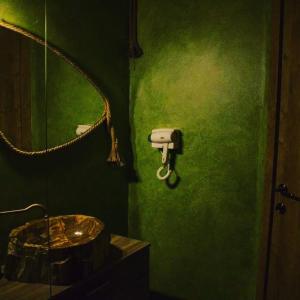 Baño verde con lavabo y espejo en Vila katherina, en Moieciu de Sus