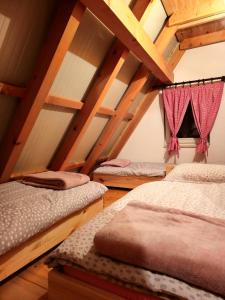 three beds in a room with wooden ceilings at Vikendica Mateo in Blidinje