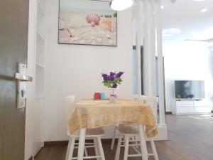 a dining room table with white chairs and a table with flowers on it at Ocean Dream Apartment Nha Trang in Nha Trang