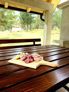 una tabla de cortar con carne y queso sobre una mesa de madera en Vikendica Mateo, en Blidinje