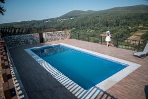a woman standing on a deck next to a swimming pool at Casa Rural A Avoa María in Campo Lameiro