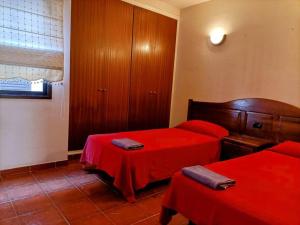 una camera con due letti con lenzuola rosse di Casa Marina-Hardling a Playa de Santiago