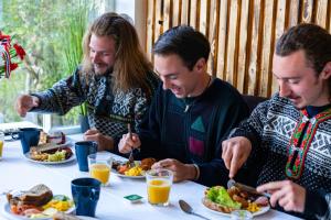 a group of three men sitting at a table eating food at Bergen Hostel Montana in Bergen