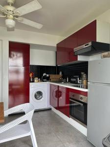 een keuken met rode kasten en een wasmachine bij Anse margot in Baie Nettle