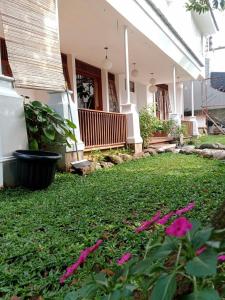 Saung Ramalea Bogor في بوغور: ساحة بها زهور وردية أمام المنزل