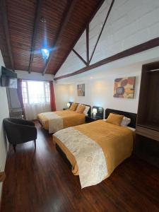 een hotelkamer met 2 bedden en een raam bij Quinta Hotel Las Buganvillas in Ambato