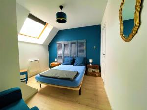 ein blaues Schlafzimmer mit einem Bett und einem Spiegel in der Unterkunft Caporizon-Le Coffre fort-Le clos de Chambord in Saint-Claude-de-Diray