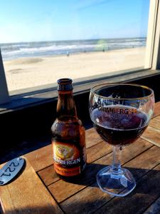 eine Flasche Bier und ein Glas Wein auf dem Tisch in der Unterkunft Romantisch Huisje nabij het strand in Julianadorp