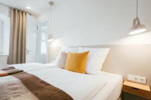 a bedroom with a bed with white sheets and yellow pillows at STADTQUARTIER Windischeschenbach in Windischeschenbach