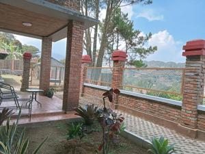 a brick patio with a table and chairs on a deck at Villa Forest Puncak in Tagalbato