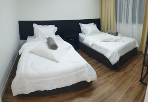 two beds in a hotel room with white sheets at D'Bangi Home Bandar Baru Bangi in Bandar Baru Bangi