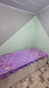 a bed with a purple comforter in a room at Kitnets Aconchegantes Próximo ao Shopping in Curitiba