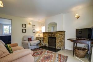 a living room with a fireplace and a television at Rose Cottage in Adderbury