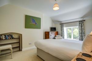 a bedroom with a large bed and a window at Rose Cottage in Adderbury