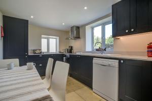 a kitchen with black cabinets and a table with chairs at Rose Cottage in Adderbury