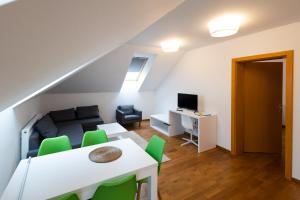 a living room with a white table and green chairs at MERKUR APARTMENTS - SELF CHECK-in in Miercurea-Ciuc
