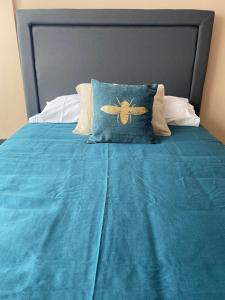 a bed with a blue comforter with a bee pillow at Cómodo, céntrico y acogedor in Santiago