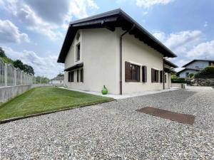 a white house with a black roof on a gravel driveway at Il Gatto e la Tartaruga Appartamento in Grignasco