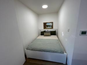um pequeno quarto com uma cama num quarto branco em Stromořadní 17 em Břeclav