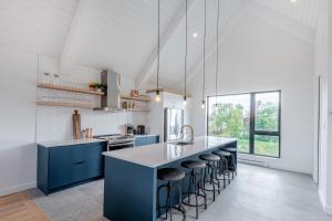 uma cozinha com armários azuis e um balcão com bancos em SOFA VILLAS MONT SAINTE-ANNE em Beaupré