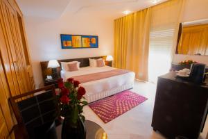 una camera d'albergo con letto e vaso di fiori di The Penthouse Suites Hotel a Tunisi