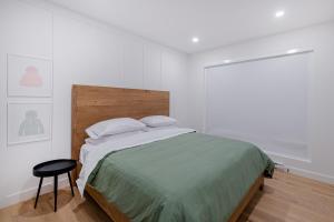 a white bedroom with a bed and a stool at SOFA VILLAS MONT SAINTE-ANNE in Beaupré
