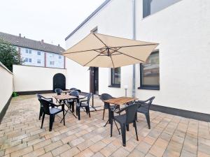 eine Terrasse mit Tischen, Stühlen und einem Sonnenschirm in der Unterkunft RAJ Living - 6 Room House with Terrace and Parking - 30 Min Messe DUS in Mönchengladbach