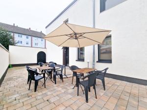 a patio with tables and chairs and an umbrella at Tolstov House - 6 Room House with Terrace and Parking - 30 Min Messe DUS in Mönchengladbach