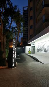 een bord voor een gebouw met een palmboom bij Apartamentos Amalia By Mc in Benidorm