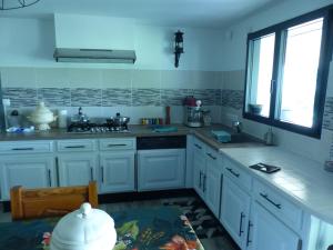uma cozinha com armários brancos, um lavatório e uma janela em Le volcan em Rochefort