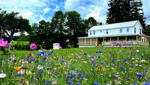 ein Blumenfeld vor einem weißen Haus in der Unterkunft French Woods Farmhouse Bed & Breakfast in Hancock