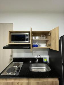 a small kitchen with a sink and a microwave at Penthouse-Loft, Laureles, Vistas a Medellín - 801 in Medellín