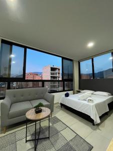 a bedroom with a bed and a couch and windows at Penthouse-Loft, Laureles, Vistas a Medellín - 801 in Medellín